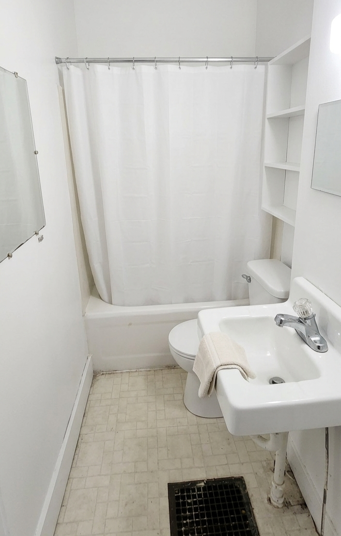306 Unit 2 Bathroom &mdash; white bathroom with tub, sink, toilet, and wall shelving